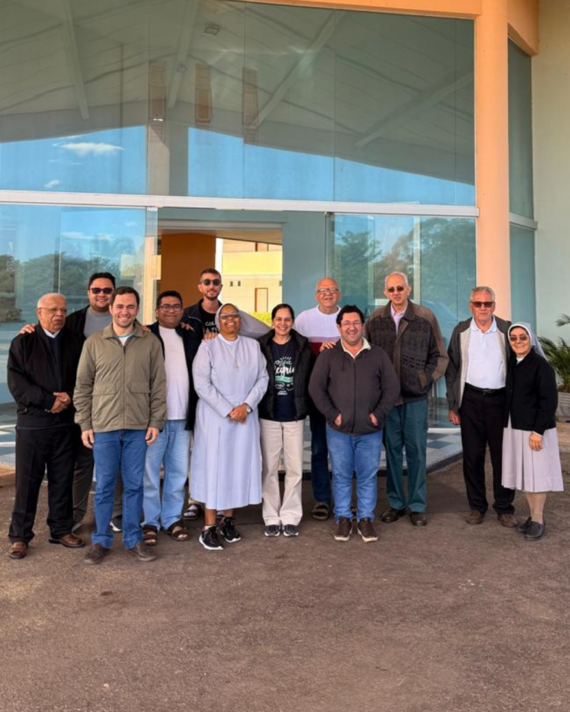 Fotografia em grupo dos frades da Fraternidade São Francisco das Chagas junto com a Irmã Rosana, reunidos durante o retiro anual no Recanto Coqueiro D'água, em Santa Luzia.